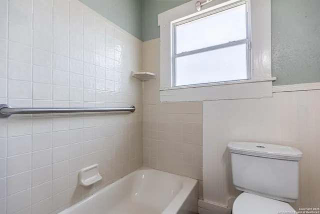 a white toilet sitting next to a bath tub