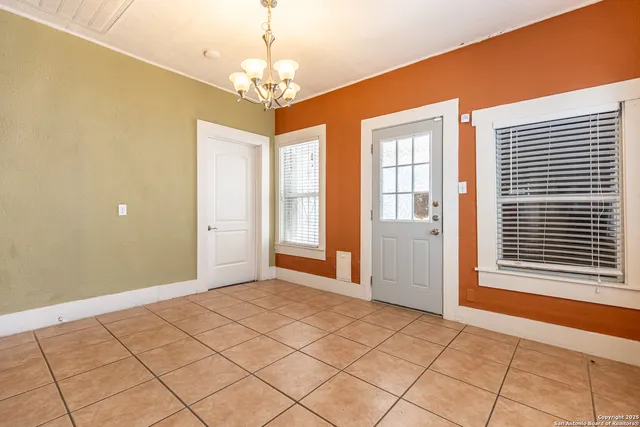 a view of an empty room with window and chandelier fan