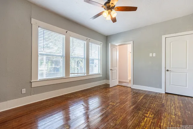 a view of an empty room with wooden floor and a window