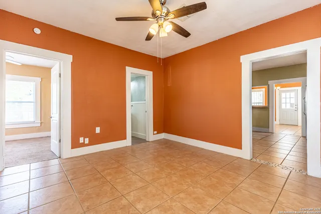 a view of an empty room with window and a chandelier fan