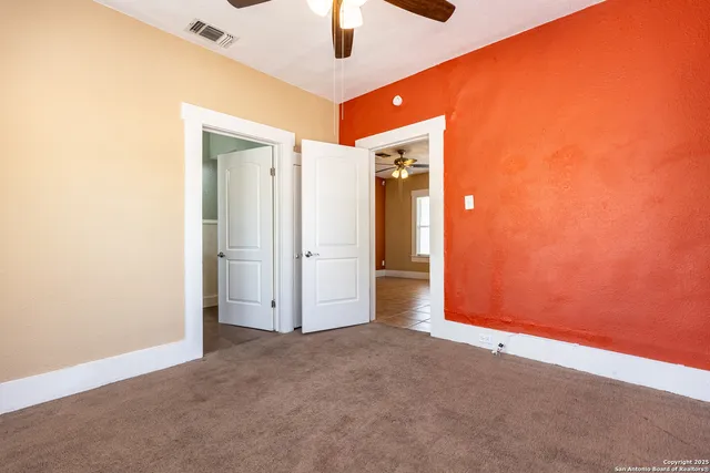 an empty room with closet and a chandelier fan