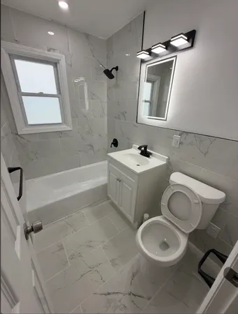 a bathroom with a toilet sink vanity tub and mirror