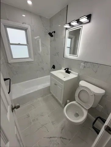 a bathroom with a toilet sink vanity tub and mirror