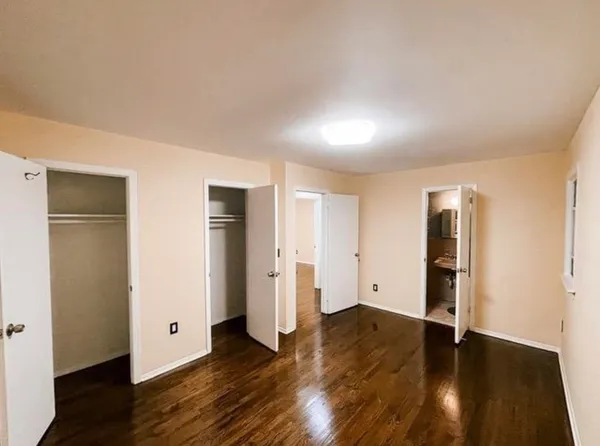 an empty room with wooden floor and closet area
