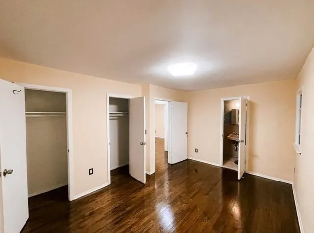 an empty room with wooden floor and closet area