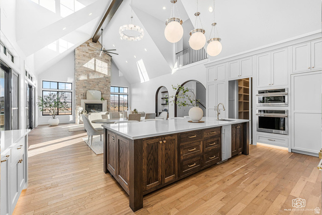 1468 South Red Cliffs Temple Lane St. George, UT 84790 - Photo 16 of 64 Two tone kitchen with two tone color scheme, a ceiling fan, a stone fireplace, light wood-style floors, and light stone counters