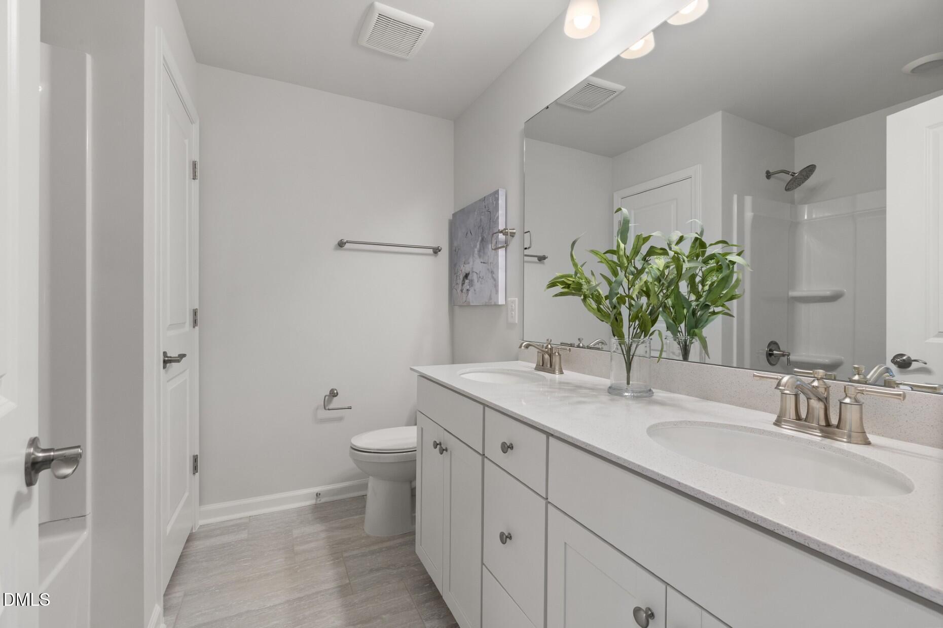 2901 Denson Road Fuquay-Varina, NC 27526 - Photo 20 of 31 a bathroom with a granite countertop sink a toilet and a mirror