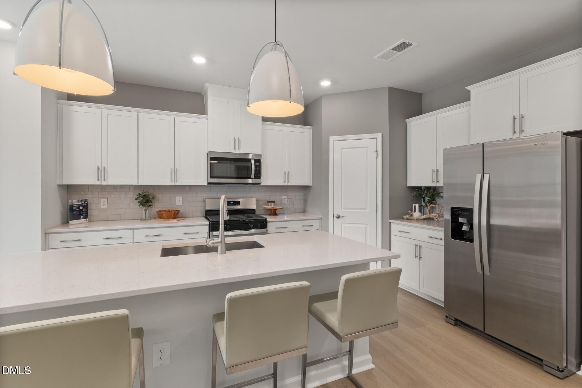 2901 Denson Road Fuquay-Varina, NC 27526 - Photo 5 of 31 a kitchen with stainless steel appliances granite countertop a refrigerator a stove a sink dishwasher a dining table and chairs with wooden floor
