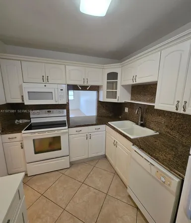 a kitchen with granite countertop white cabinets and white appliances