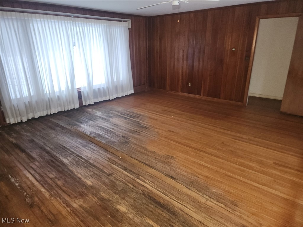 7516 Mayfield Road Chesterland, OH 44026 - Photo 9 of 21 Spare room featuring wood finished floors, a ceiling fan, and wooden walls