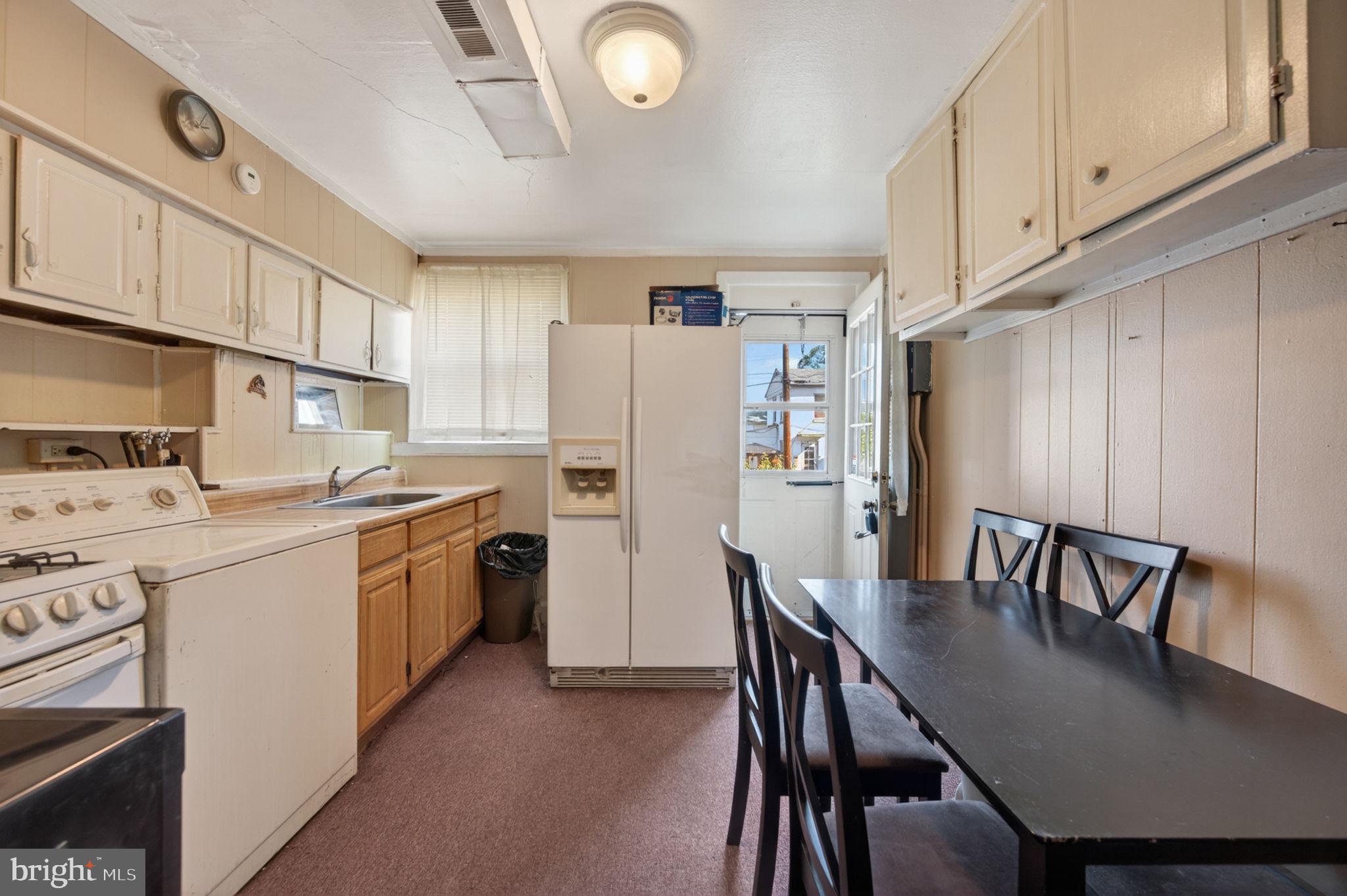 952 Armistead Way Baltimore, MD 21205 - Photo 2 of 13 a kitchen with a table chairs refrigerator and cabinets