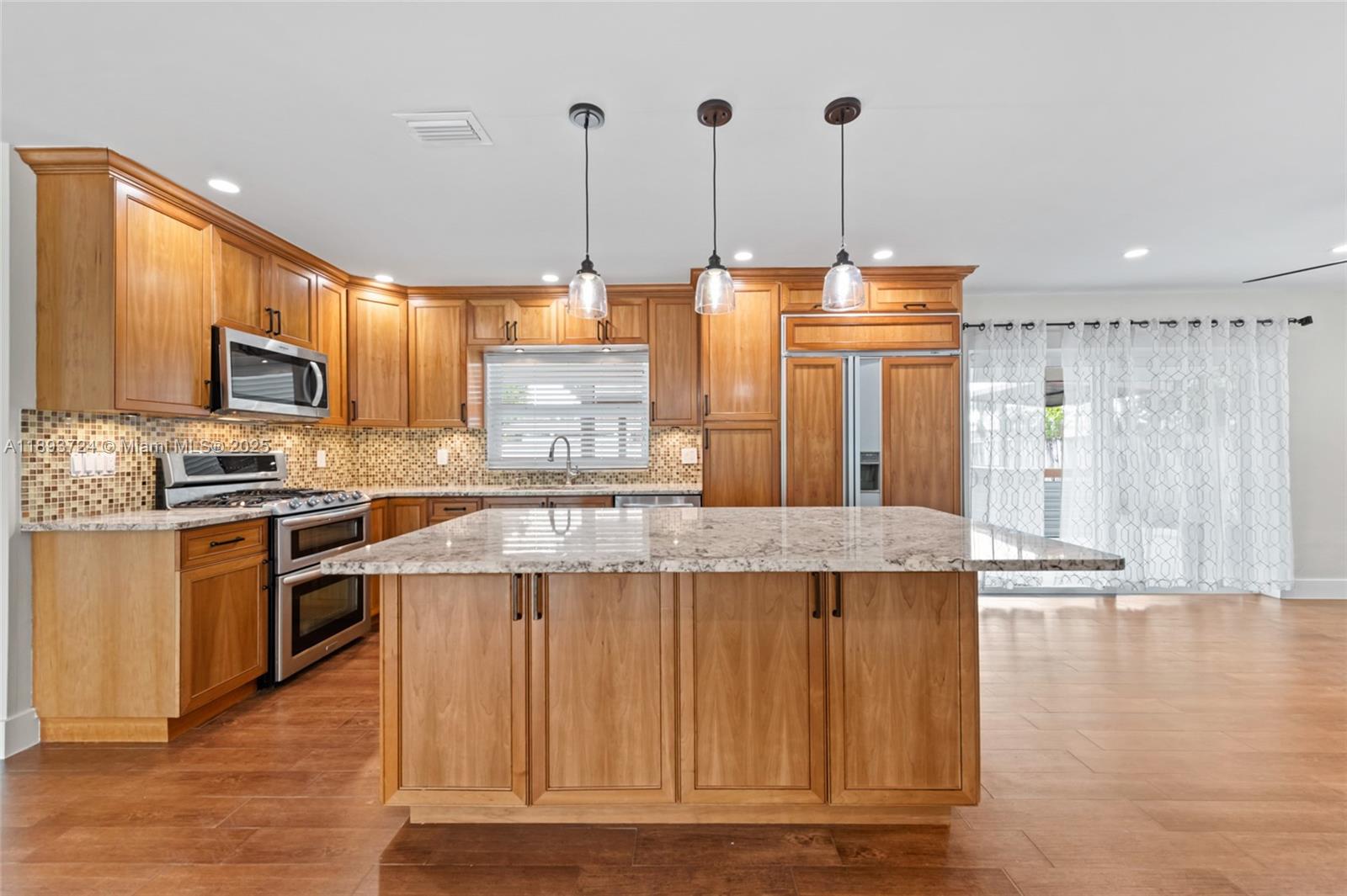 8440 Southwest 201st Street Cutler Bay, FL 33189 - Photo 11 of 31 a kitchen with kitchen island granite countertop wooden cabinets and white appliances
