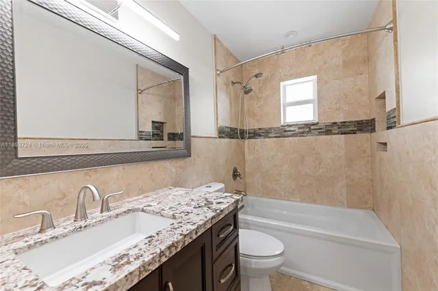 a bathroom with a granite countertop sink mirror vanity and toilet