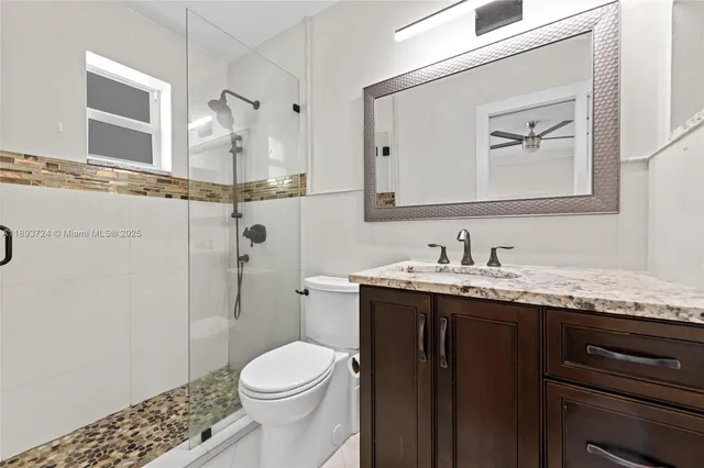 a bathroom with a granite countertop sink mirror and toilet