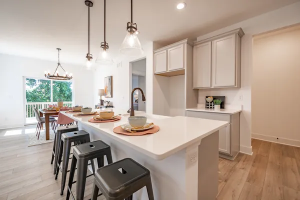 a open dining room with wooden floor appliances and a chandelier