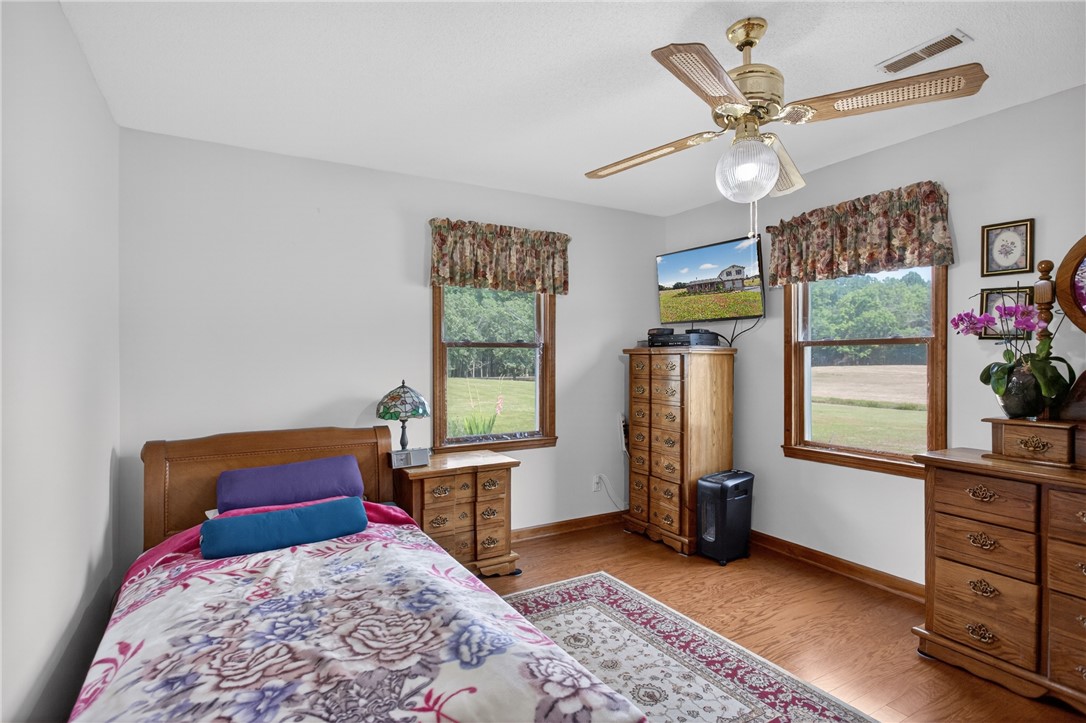 145 State Rd S-4-935 Pendleton, SC 29670 - Photo 15 of 47 A quiet bedroom featuring warm hardwood flooring and ample natural light through a pair of windows overlooking scenic outdoor vistas.