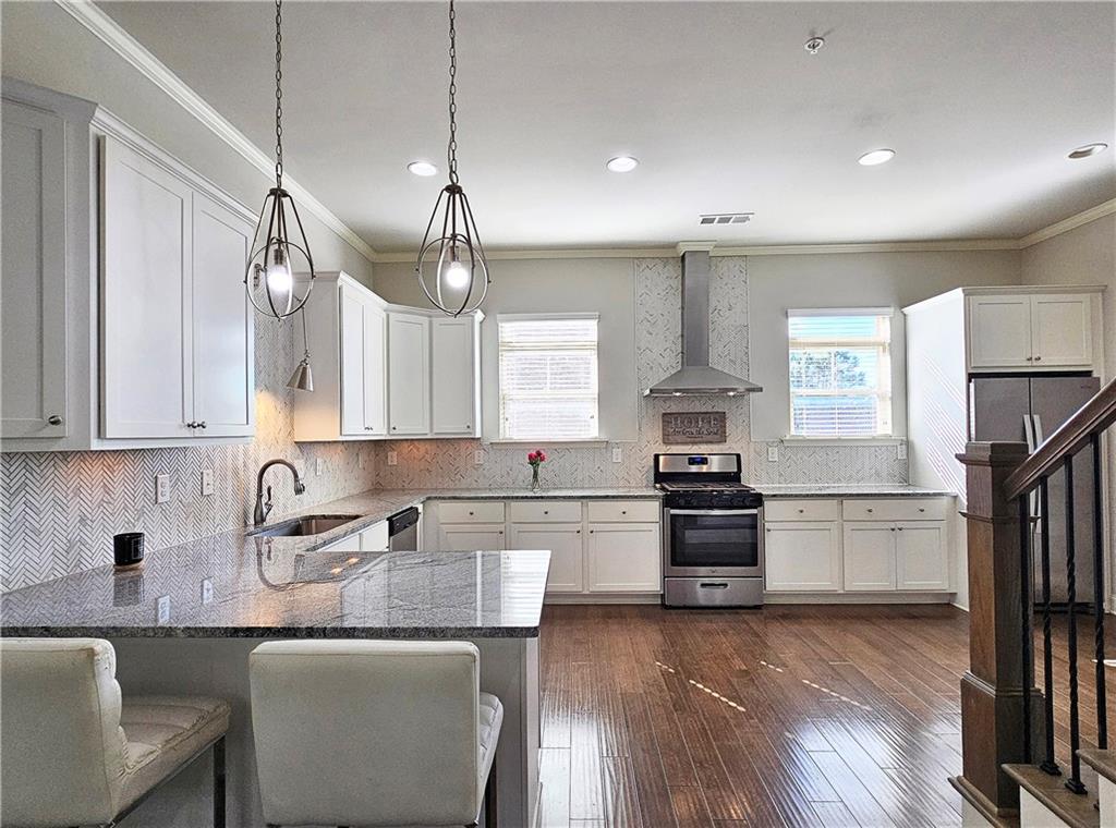 1212 Stone Castle Circle Smyrna, GA 30080 - Photo 13 of 39 a kitchen with stainless steel appliances granite countertop a stove top oven a sink dishwasher a dining table and chairs with wooden floor