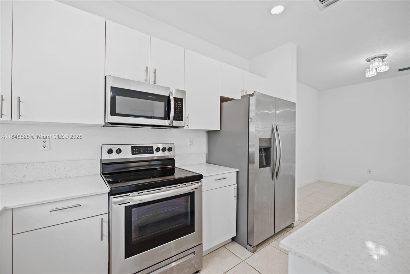 12965 Southwest 233rd Terrace Homestead, FL 33032 - Photo 9 of 25 a kitchen with stainless steel appliances white cabinets white stove a microwave and a refrigerator