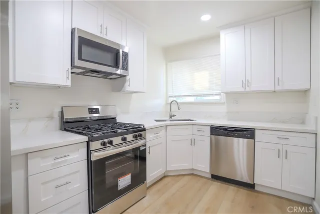a kitchen with cabinets stainless steel appliances and wooden floor
