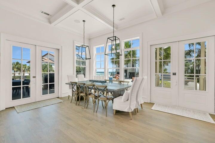 410 Beachfront Trail Santa Rosa Beach, FL 32459 - Photo 9 of 102 a dining room with wooden floor a chandelier a glass table and chairs