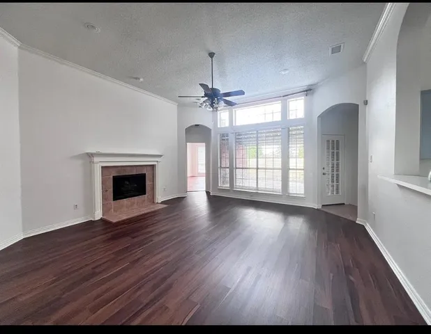 an empty room with wooden floor fireplace and windows