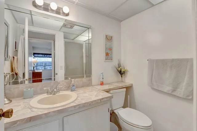 a bathroom with a granite countertop toilet sink and mirror