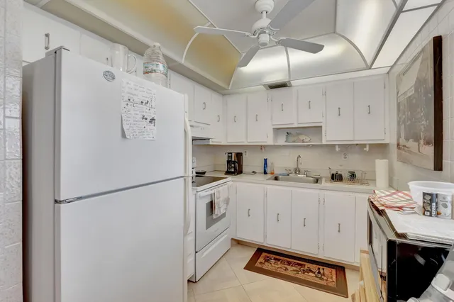 a kitchen with stainless steel appliances a refrigerator a sink and white cabinets