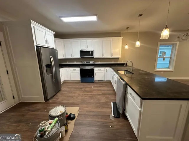 a large kitchen with stainless steel appliances granite countertop a large counter top a stove a sink and a refrigerator