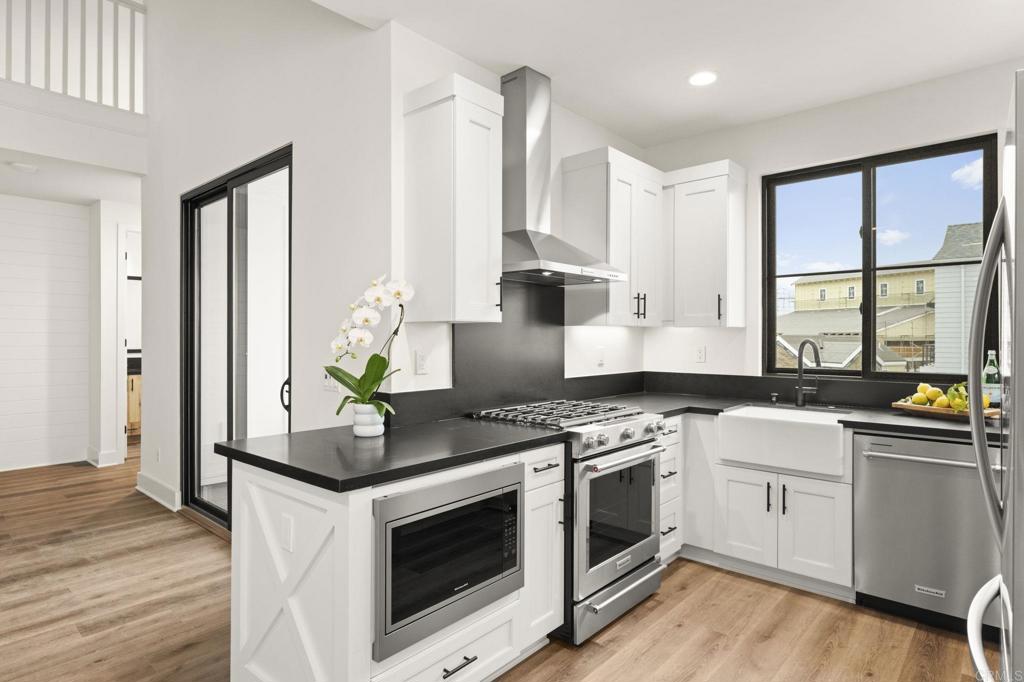 1303 Bergamo Encinitas, CA 92024 - Photo 4 of 21 a kitchen with stainless steel appliances white cabinets and wooden floor