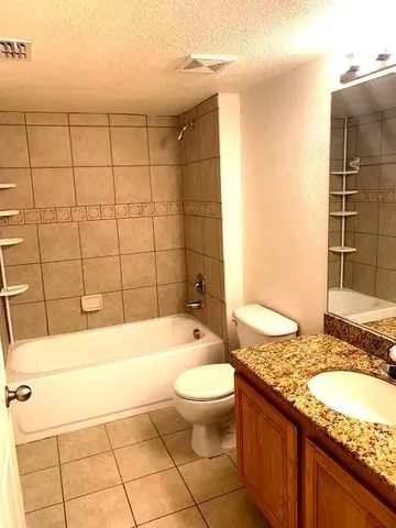 a bathroom with a granite countertop sink a toilet and bathtub