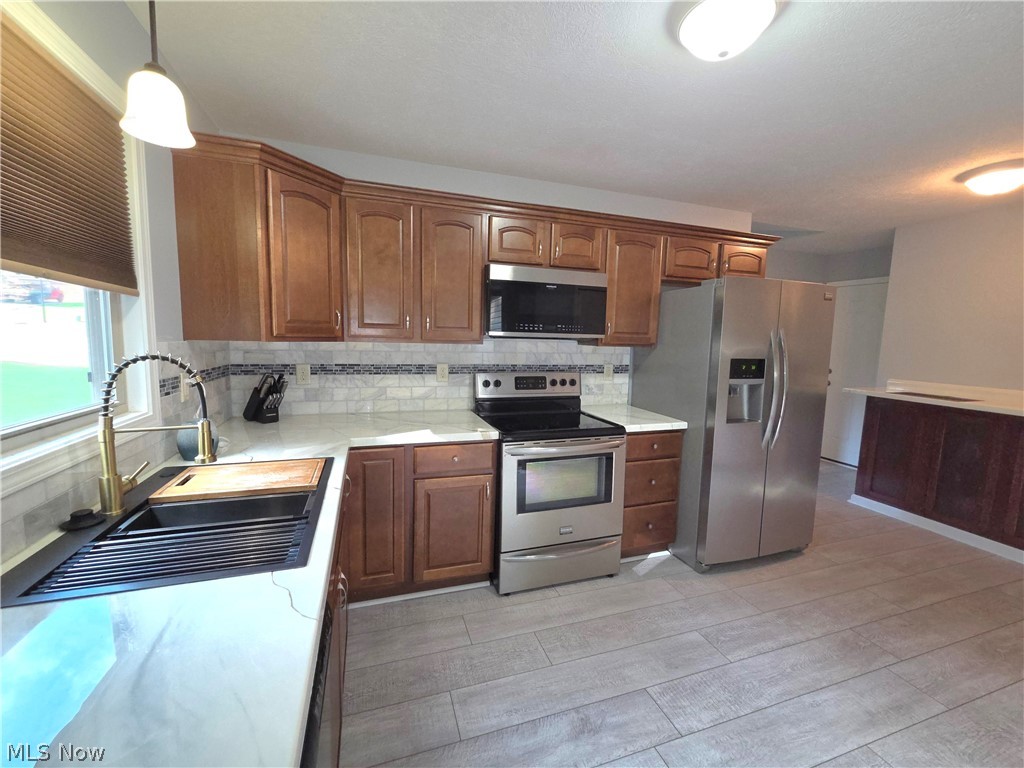 202 Home Street Rittman, OH 44270 - Photo 9 of 23 Wood-finish cabinetry complemented by stainless steel appliances, white countertops, and a subway tile backsplash