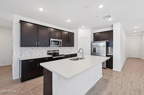 a kitchen with stainless steel appliances kitchen island granite countertop a refrigerator a sink dishwasher a stove and a dining table with wooden floor