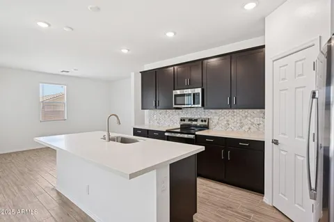 a kitchen with a sink a microwave a refrigerator and cabinets