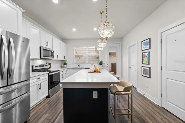 a kitchen with a refrigerator a stove top oven a sink dishwasher and white cabinets with wooden floor