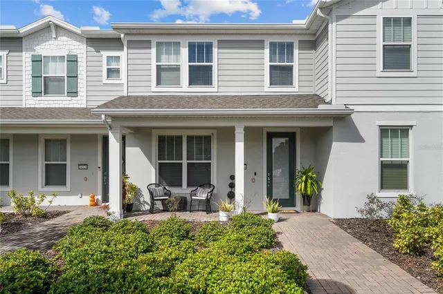 front view of a brick house with potted plants and a bench
