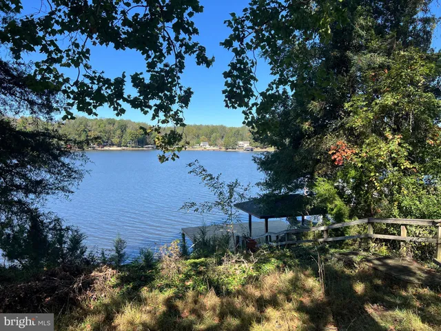 a view of a lake with lawn chairs under an umbrella