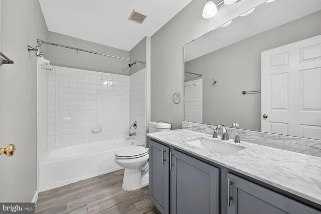 a bathroom with a granite countertop sink a toilet and shower