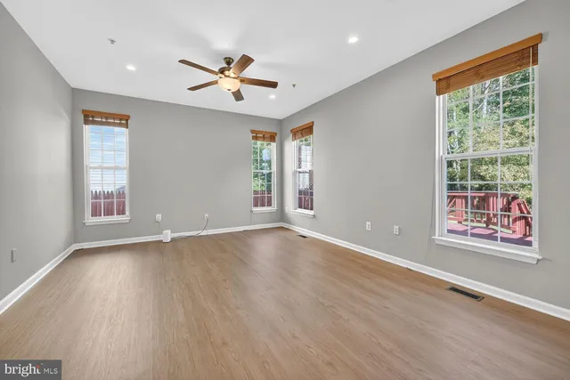 a view of an empty room with a window and wooden floor