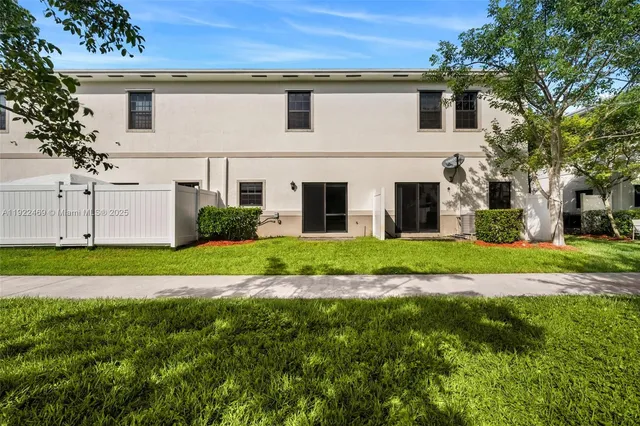 a view of a white house next to a yard and large trees