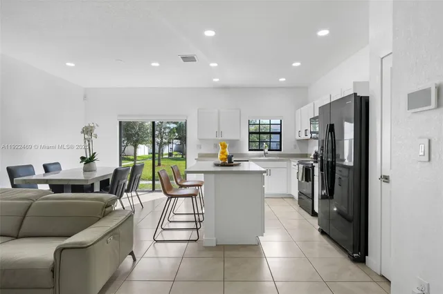 a kitchen with stainless steel appliances granite countertop a refrigerator and a view of living room