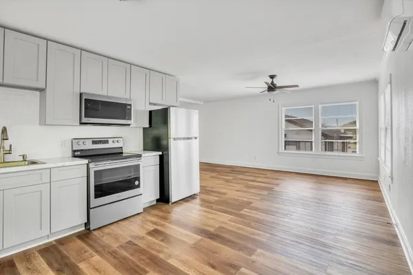 a kitchen with granite countertop a refrigerator stove and wooden floor