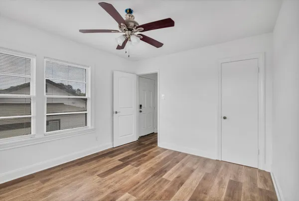 a view of empty room with wooden floor and fan