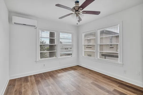 a view of an empty room with a window and wooden floor
