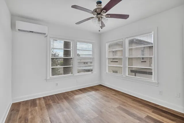 a view of an empty room with a window and wooden floor
