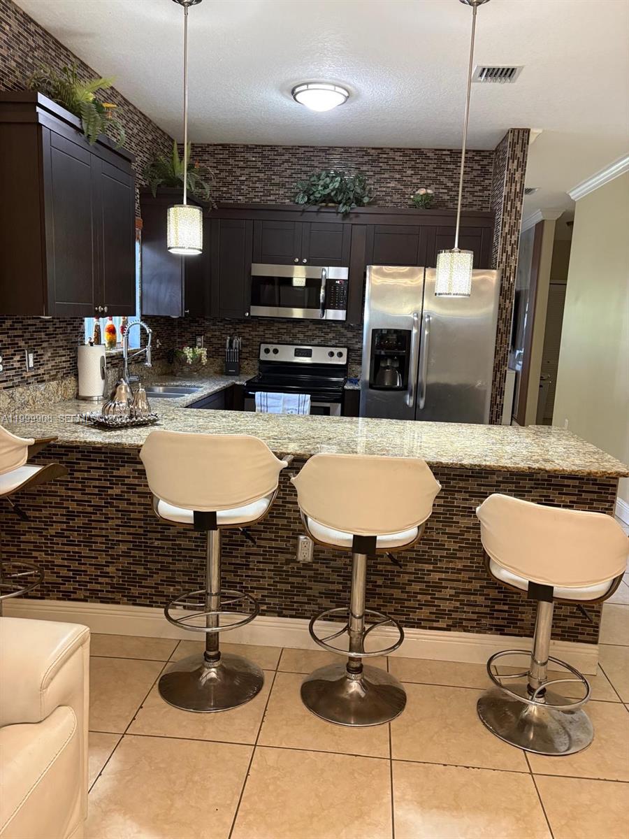 1394 West 30th Street Hialeah, FL 33012 - Photo 7 of 21 a kitchen with granite countertop kitchen island stainless steel appliances a sink and a living room view