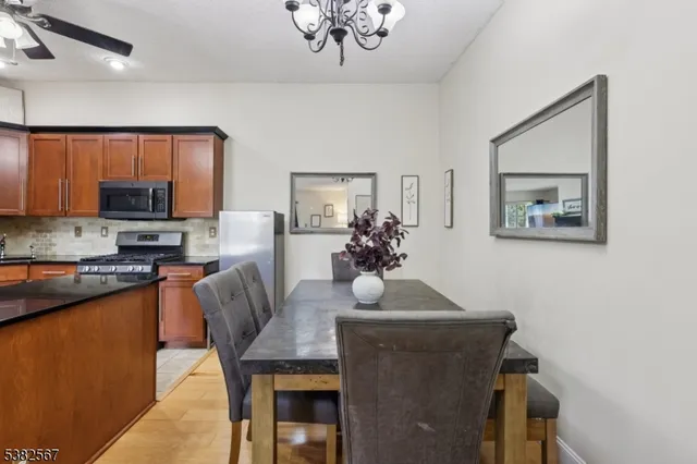 a living room with stainless steel appliances furniture a chandelier and a dining table