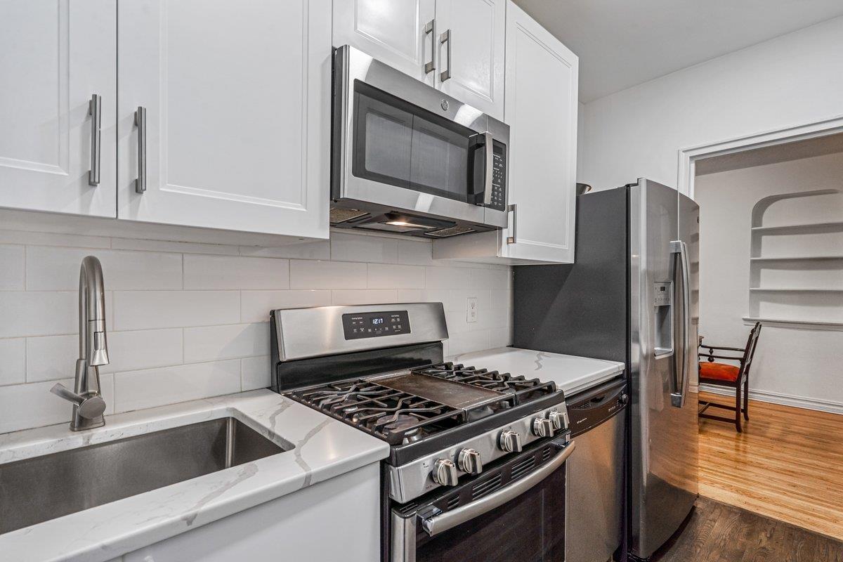 99-45 67th Road, Unit 406 Queens, NY 11375 - Photo 1 of 1 Kitchen featuring stainless steel appliances, white cabinetry, dark wood-type flooring, and sink