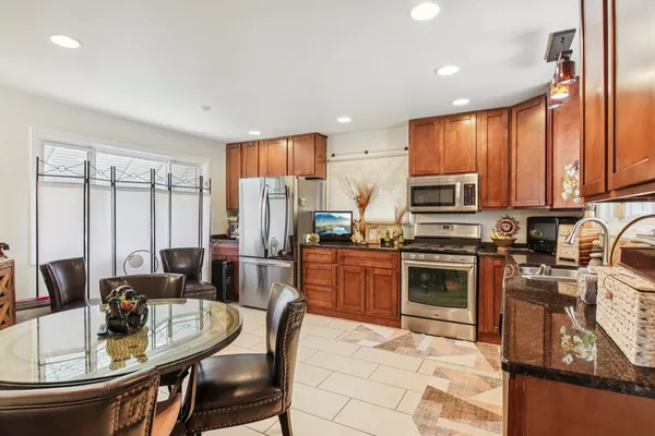 a kitchen with stainless steel appliances granite countertop a stove top oven a sink dishwasher a dining table and chairs with wooden floor