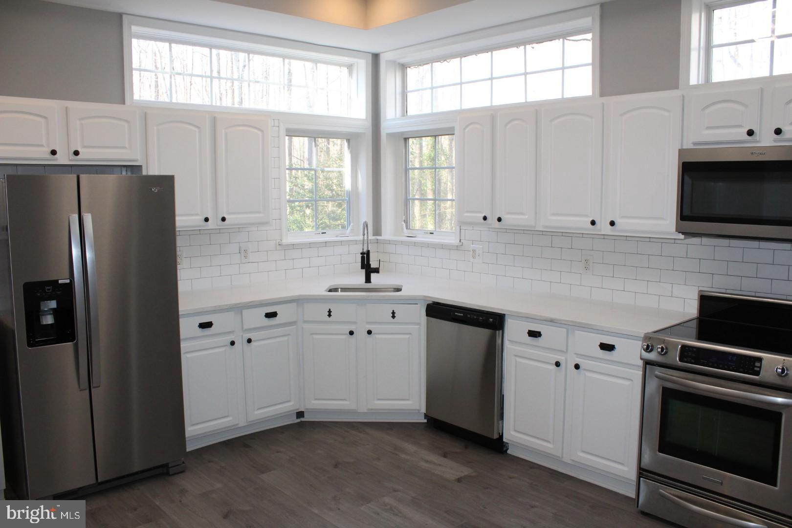 a kitchen with stainless steel appliances white cabinets a sink and a window