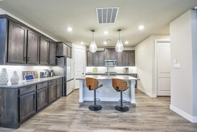 a kitchen with kitchen island granite countertop a sink and refrigerator